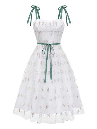 Vue de face en studio de la robe en résille blanche mettant en valeur le décolleté en cœur et la jupe à volants.