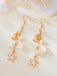 Gold earrings with starfish and shell designs on a beige background