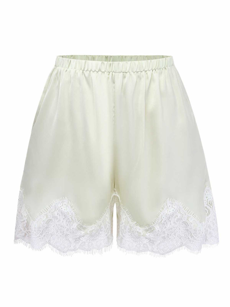 Studio front view of the cream-colored satin pajama shorts featuring an elastic waistband and wide lace-trimmed legs.