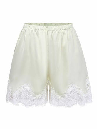 Studio front view of the cream-colored satin pajama shorts featuring an elastic waistband and wide lace-trimmed legs.