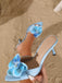 Angled shot of a single light blue satin mule showcasing the slender stiletto heel and floral embellishment.