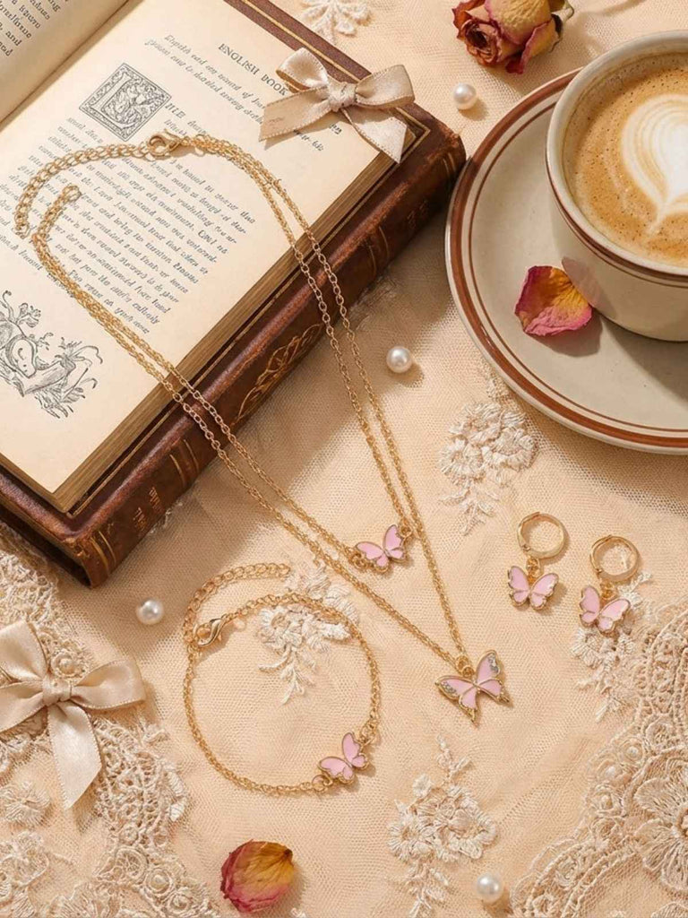 Gold butterfly necklace on a lace tablecloth with a book and cup of coffee.