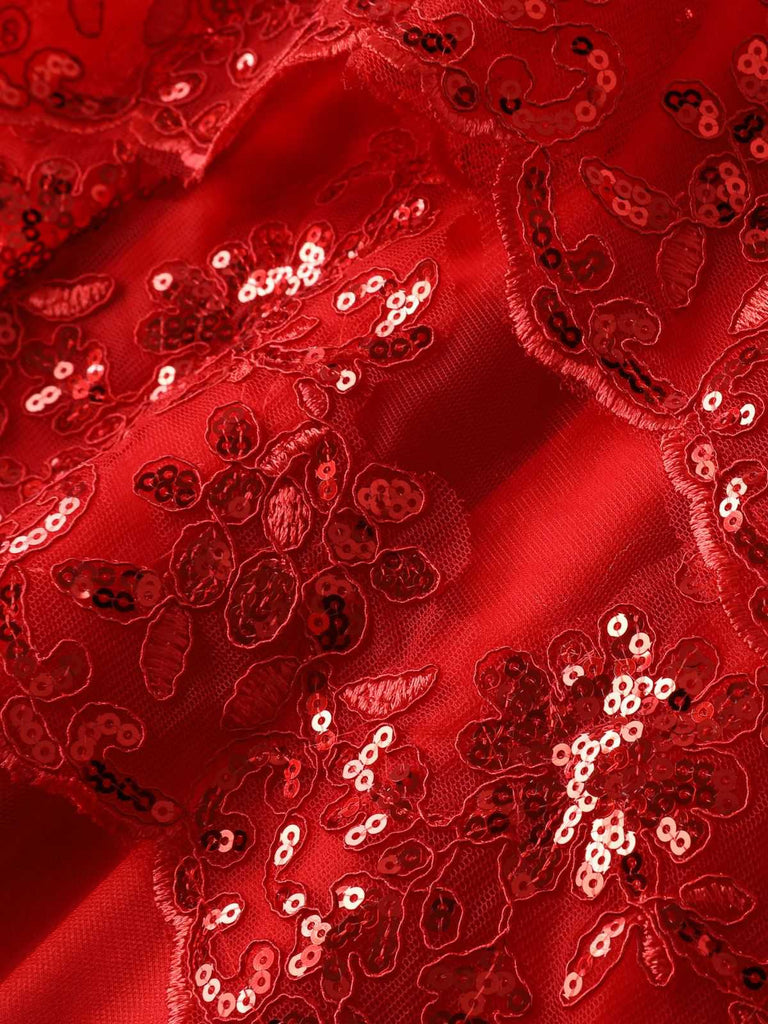 Macro view of the red tulle fabric adorned with floral lace appliqués and shimmering sequins.