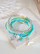 Stack of beaded bracelets with charms on a textured stone surface